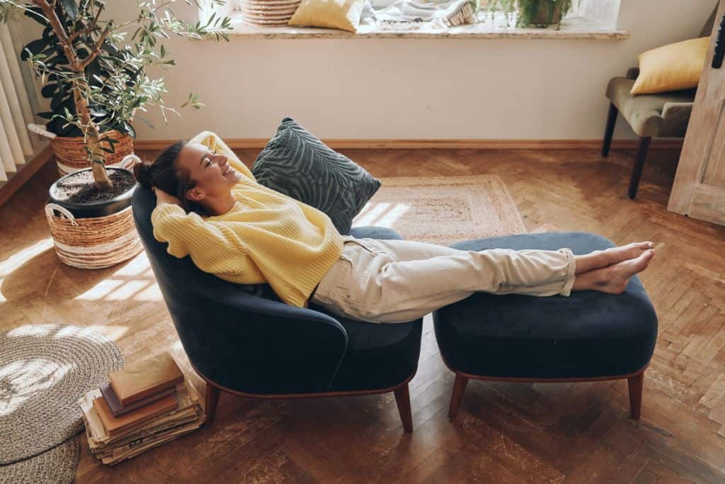 Top view of happy woman keeping eyes closed while relaxing in comfortable chair at home