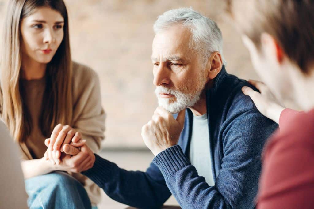 man receiving comfort and support from family during therapy session