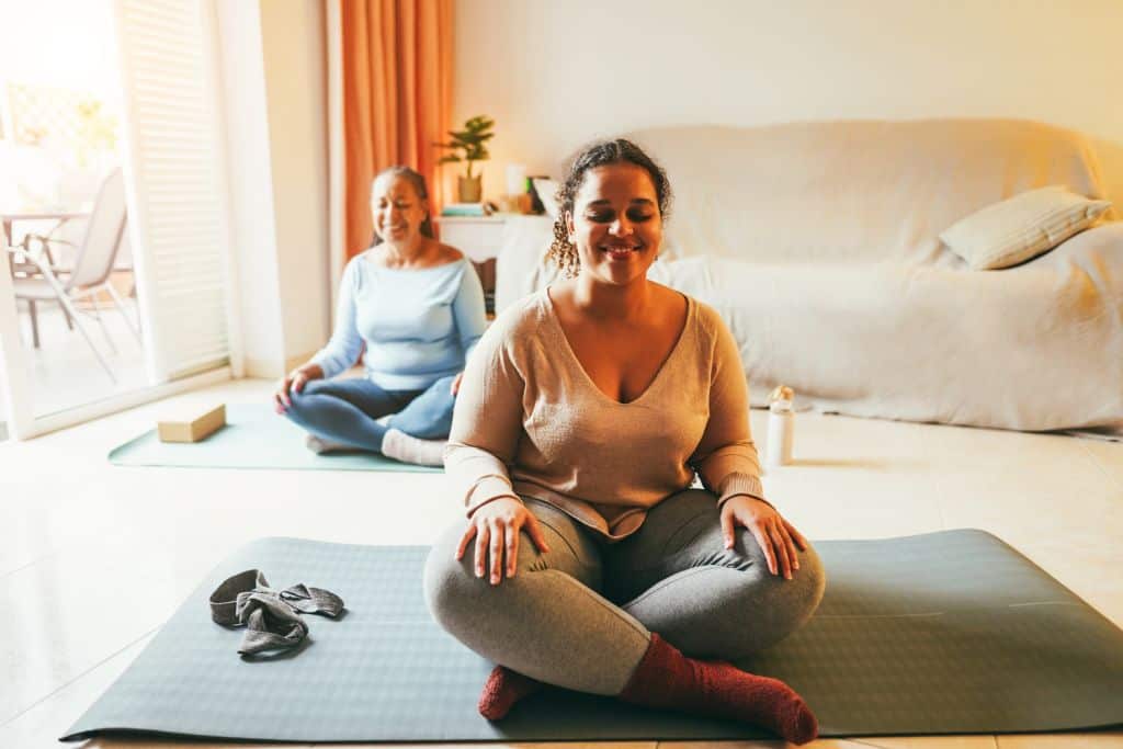Mother And Daughter Doing Yoga Exercises At Home