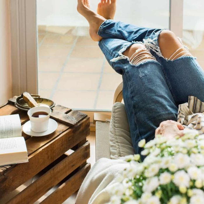 image of a woman relaxing at home in sunny day, drinking tea, reading book